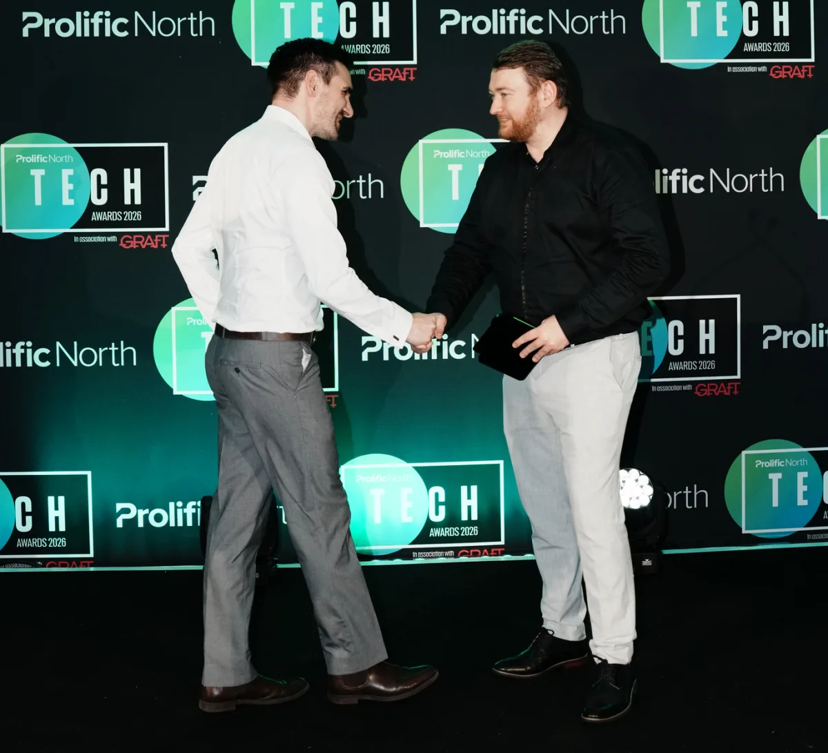 Mike shaking hands with the award presenter on stage after collecting the award.